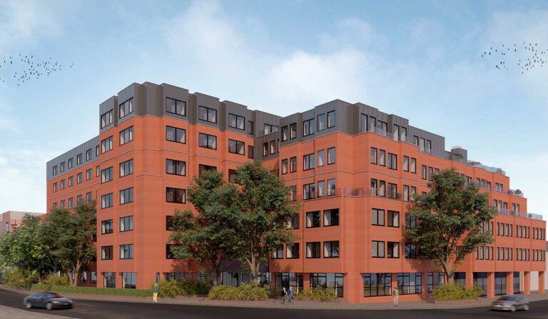A modern commercial building with a red brick exterior and flat roof converted into functional space, surrounded by trees, on a sunny day.